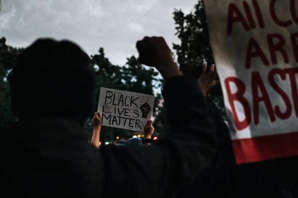 Hands holding up various Black Lives Matter protest signs